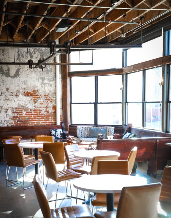 a dining room with tables and chairs in front of a brick wall