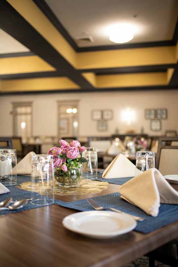 A dining table set with a napkin, glasses, and flowers.
