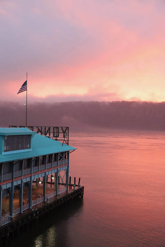 a foggy sunrise over the lake with a pier and a flag