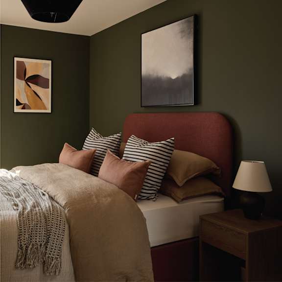 A bedroom with a bed, pillows, a blanket, a nightstand, and a ceiling fan.