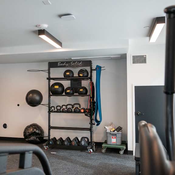 a fitness room with weights on a rack and a door