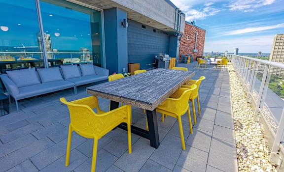 a patio with a wooden table and yellow chairs