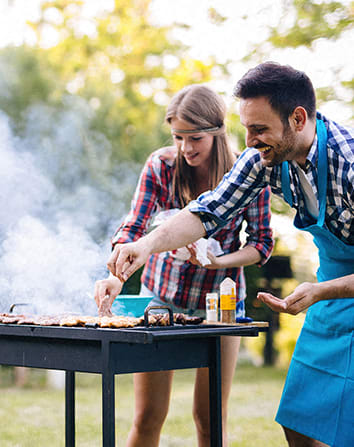 a man and woman cooking on a barbecue