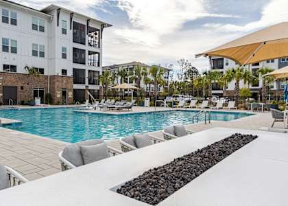 A large swimming pool with lounge chairs and a black rock border.