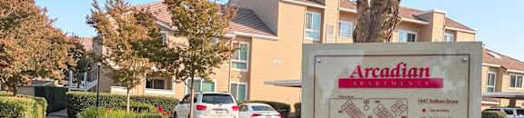 A sign for Arcadian apartments stands in front of a building.