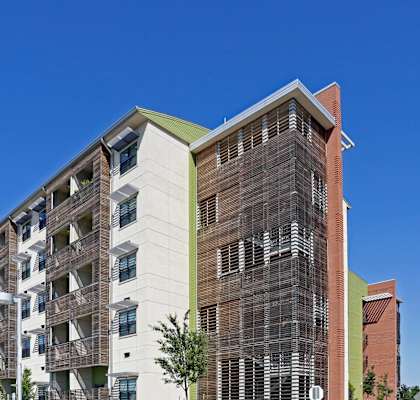 A modern multi-story building with a parking lot in front.