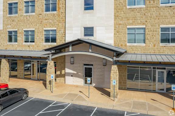 A parking lot in front of a building with a stone facade.