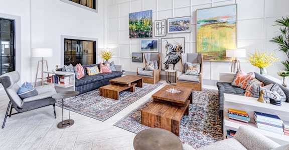 A living room with a grey couch, a wooden coffee table, and a painting on the wall.