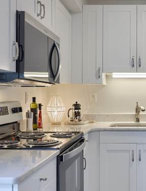 A modern kitchen with white cabinets and stainless steel appliances.