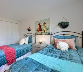 A bedroom with two beds and a painting on the wall.