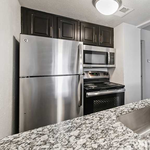 A kitchen with a stainless steel refrigerator and microwave.