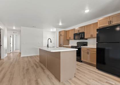 A kitchen with wooden cabinets and a black refrigerator.