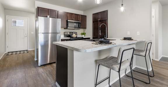 A kitchen with a white countertop and a stainless steel refrigerator.