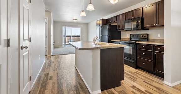 A kitchen with black appliances and brown cabinets.