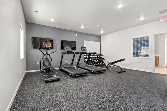 A spacious gym with treadmills, elliptical machines, and a weight bench.