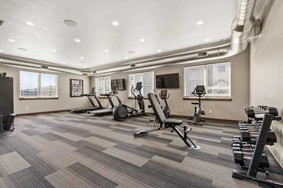 A gym with a variety of equipment including treadmills, weights, and exercise machines.