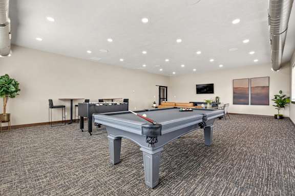 A room with a pool table and a tv on the wall.