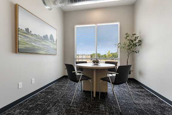 A room with a table, chairs and a painting on the wall.