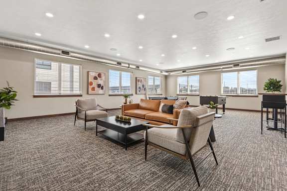 A spacious living room with a grey carpet and furniture.