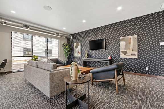 A living room with a grey couch, a wooden table, and a black chair.