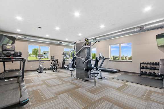 A spacious gym with a variety of equipment including treadmills, stationary bikes, and weight machines.