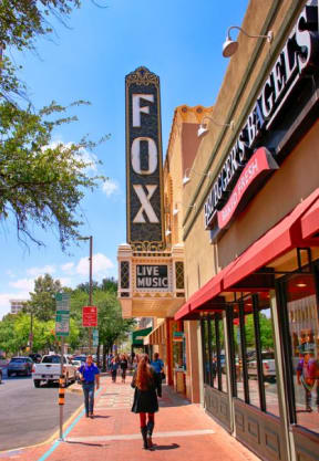 people walking on a sidewalk in front of a theater sign at Promontory, Tucson, AZ, 85704