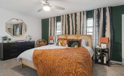 a bedroom with green walls and an orange blanket on the bed