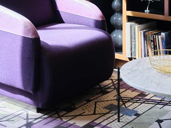 A purple chair sits in front of a bookshelf.