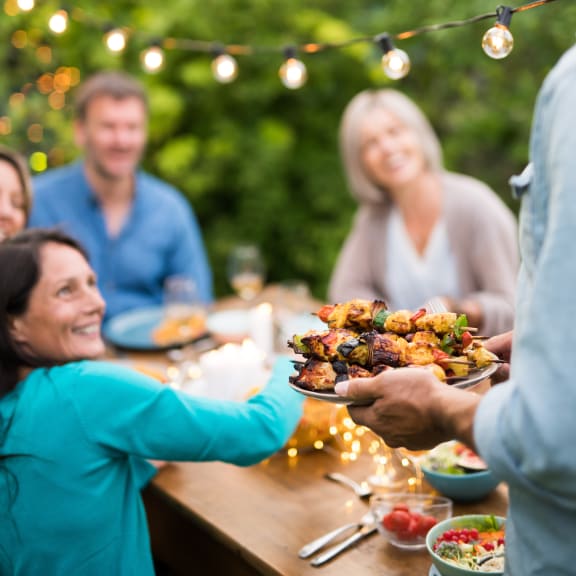 a person handing a plate of food to another person at a holiday party