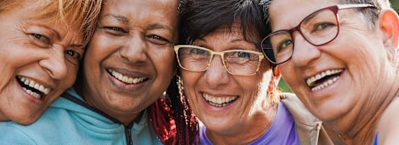 Three women are smiling and hugging each other.