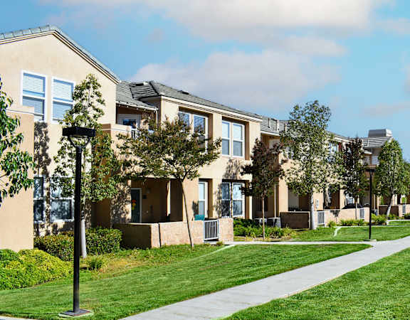 a row of apartments on a sidewalk with grass and trees