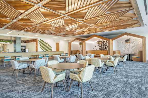 A modern dining room with a wooden ceiling and grey carpet.