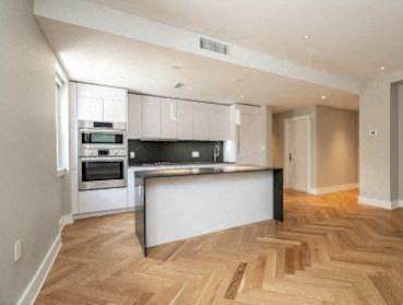 A modern kitchen with wooden flooring and stainless steel appliances.