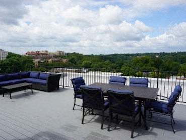 A balcony with a table and chairs overlooking a cityscape.