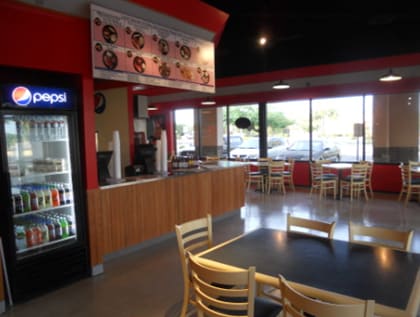 Tom's BBQ Chandler dining area with a table and chairs and a refrigerator with a drink in it at Chandler Heights, Chandler, AZ