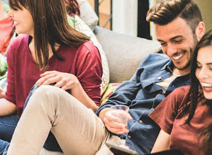 A group of people sitting on a couch with one person holding a tablet.