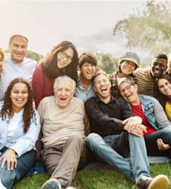A group of people sitting on the grass in a park.