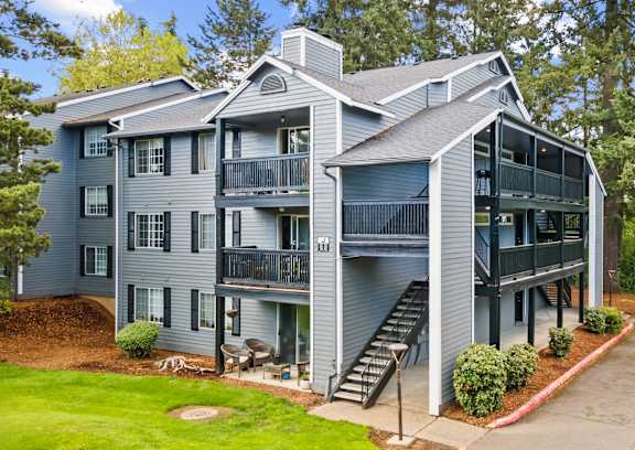 A grey two story apartment building with a balcony on the second floor.