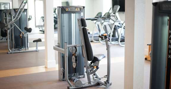 A gym with a rowing machine in the foreground.