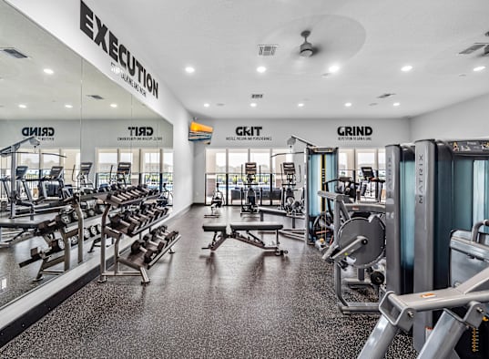 a gym with weights and cardio equipment in a building with glass doors
