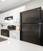 a white kitchen with a black refrigerator and a sink
