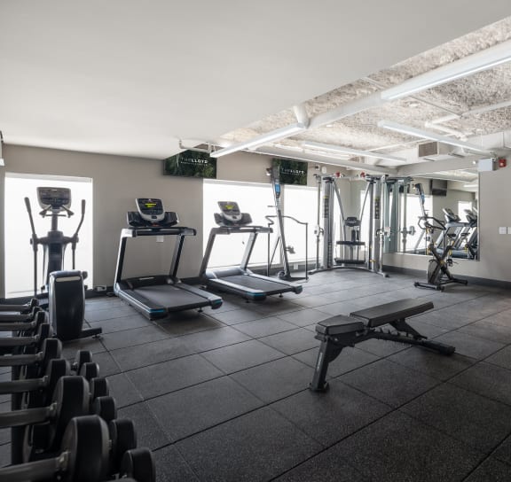a gym with treadmills and other exercise equipment in a room with a window