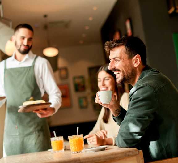 A waiter serves food to a man and a woman at a table.