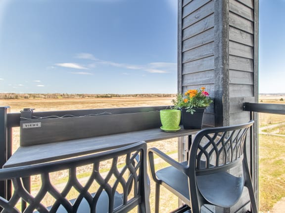 a balcony with a chair and a table with flowers on it