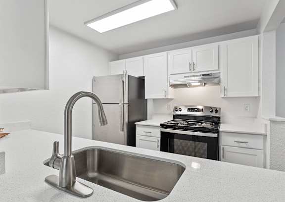A modern kitchen with a stainless steel sink and refrigerator.