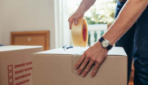 A person taping a box shut.