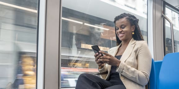 a woman sitting on a subway train looking at her phone