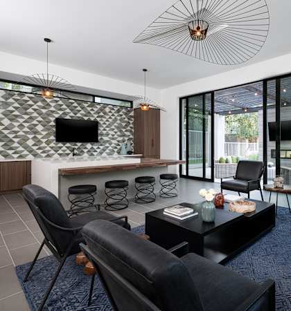 A modern living room with black leather chairs and a patterned wall.