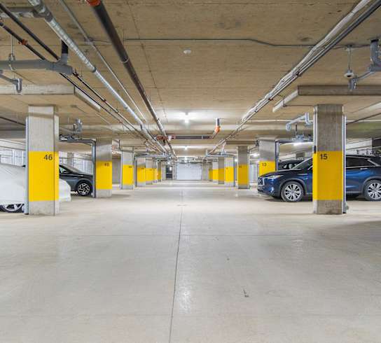 the underground parking garage of an apartment building with parked cars