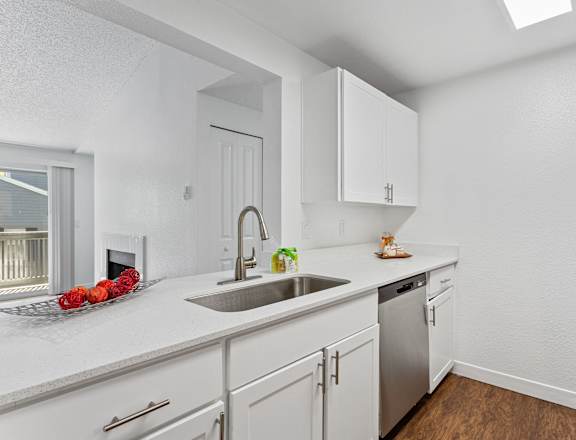 A kitchen with white cabinets and a stainless steel refrigerator.